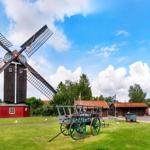 Historischer Windmühle mit grünem Wagen auf grünem Rasen.