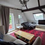 Wohnzimmer mit Sofa, Couchtisch und TV unter Holzbalkendecke.