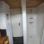 Badezimmer mit Dusche, Spiegel und Holzregal