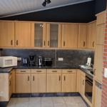 Küche mit Holzschränken, Steinrückwand und rotem Backsteinwand.