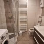 Badezimmer mit Dusche, Toilette, Waschbecken und Waschmaschine.