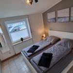 Schlafzimmer mit Doppelbett, Fenster und Wandbildern.