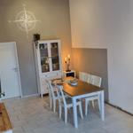 Esszimmer mit Tisch, Stühlen und Glasvitrine an der Wand.