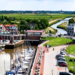 Hafen mit Booten, Grünflächen und modernen Gebäuden am Fluss.