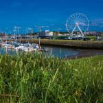 Hafen mit Booten und Riesenrad im Hintergrund