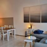 Wohn- und Essbereich mit Sofa, Tisch und Wandbildern.