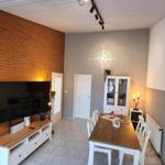 Wohn- und Essbereich mit Fernseher, Tisch und Schrank.