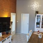 Wohn- und Essbereich mit Fernseher, Tisch und Schrank.