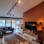 Wohn- und Essbereich mit Sofa, Fernseher und Holztisch.