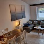 Wohn- und Essbereich mit Sofa, Tisch und Wandbildern.