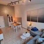 Wohn- und Essbereich mit Sofa, Tisch und Wandbildern.