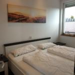 Zwei Betten mit weißen Bettwäsche, Wandbild und Fenster mit Jalousie.