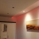 Wand mit Strandbild, weiße Schrankwand und Deckenleuchten.