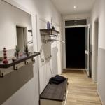 Flur mit Spiegelschrank, Kleiderständer und Holzboden.