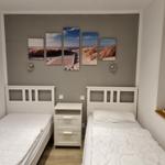Zwei Einzelbetten mit weißer Bettwäsche, Wandbild mit Strandmotiv und Nachttisch.