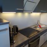 Küche mit Herd, Spüle und Dunstabzug.