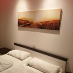 Schlafzimmer mit Bett, Wandbild und Nachttisch.