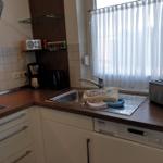 Kitchen with sink, toaster, and coffee machine next to window with white curtains.