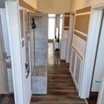 Hallway with wooden floor and wall paneling, door to bedroom and bathroom