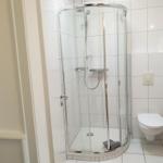 Bathroom with shower, toilet, and white tiles.