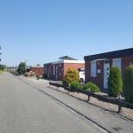 Row of holiday homes with paved path and green surroundings.