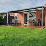 Terrace with seating and green lawn in front of a brick house.