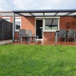 Deck with seating and garden in front of red brick house.