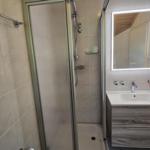 Badezimmer mit Dusche, Waschbecken und beleuchtetem Spiegel.