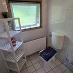 Badezimmer mit Toilette, Fenster und weißen Fliesen.