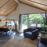 Wohn- und Essbereich mit Sitzgelegenheiten, Tisch, TV und Blick auf den Garten.