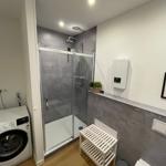 Badezimmer mit Dusche, Waschmaschine und Holzboden.