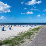 Strand mit bunten Liegestühlen und Promenade unter blauem Himmel.