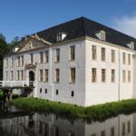 Weißes Schloss mit Brücke und Wasserreflexion