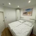 Schlafzimmer mit Doppelbett, weißen Möbeln und Wandbild.