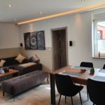 Wohn- und Essbereich mit Sofa, Tisch und Stühlen. Wandbild und Fenster sichtbar.