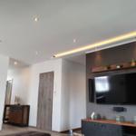 Wohnzimmer mit Fernseher, Sideboard und Beleuchtung.