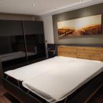 Schlafzimmer mit Doppelbett, Kleiderschrank und Wandbild.