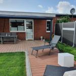 Terrasse mit Gartenmöbeln, Liegestühlen und Rasenfläche.