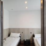 Zwei Einzelbetten mit weißer Bettwäsche und einem Nachttisch dazwischen.