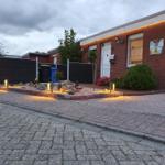 Rotes Backsteinhaus mit beleuchteter Fassade und gepflastertem Vorplatz.