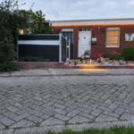 Einfamilienhaus mit Garten, Beleuchtung und gepflastertem Vorplatz.