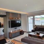 Wohnbereich mit Sofa, TV und Küche im Hintergrund.