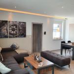 Wohn- und Essbereich mit Sofa, Tisch und Wandbildern.