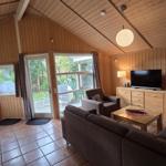 Wohn- und Essbereich mit Holzwand, Sofa, TV und Terrassentür.