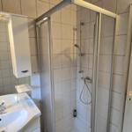 Badezimmer mit Dusche, Waschbecken und Spiegel.