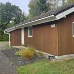 Holzhaus mit Nummer 122, Garten und Wald im Hintergrund.