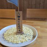 Willkommen-Schild mit Segelboot auf Teller mit Blumenkuchen