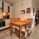 Küche mit Essbereich, Holztisch und -stühle, Wandbilder und Pendelleuchte.