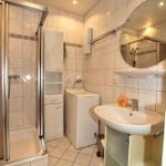 Badezimmer mit Dusche, Waschmaschine und Waschbecken