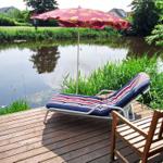 Terrasse mit Liegestuhl und Sonnenschirm am Wasser